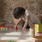 A young child plays with wooden mandala pieces.  They are arranging the wooden pieces into a pattern.