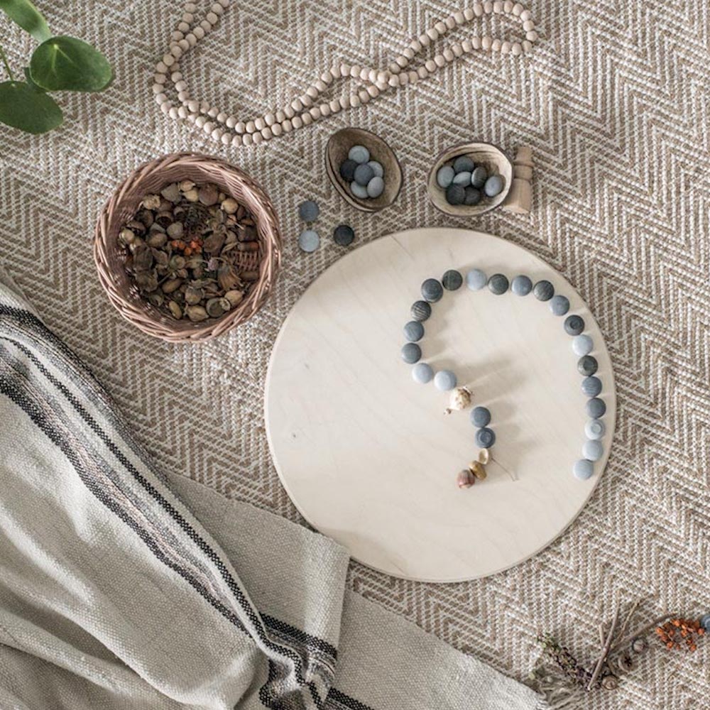 A play scene showing nature parts and wooden grey stones in a curved path on a wooden surface.